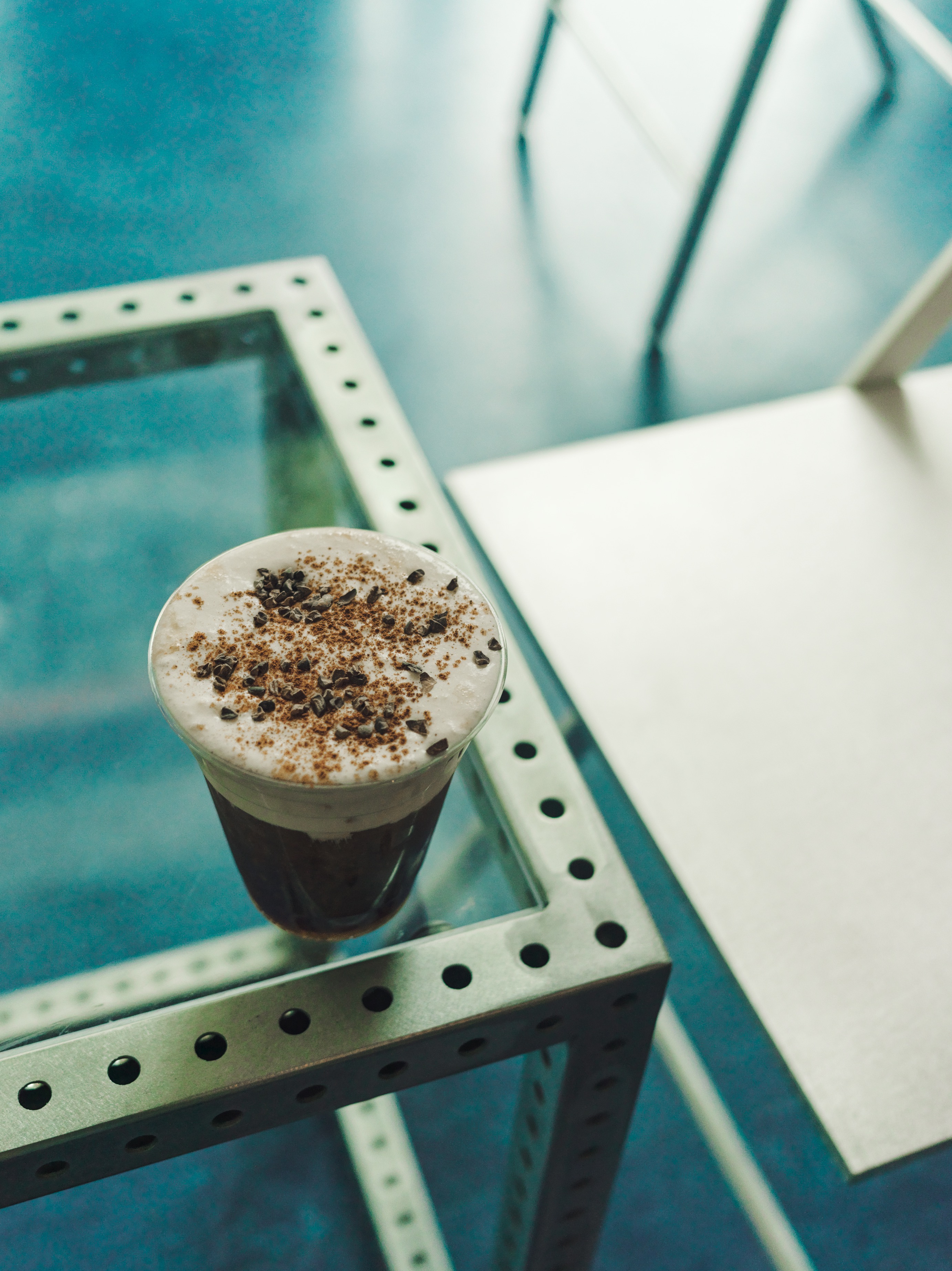 Iced coffee topped with cinnamon on a glass table at Jurassic Magic MacArthur Park