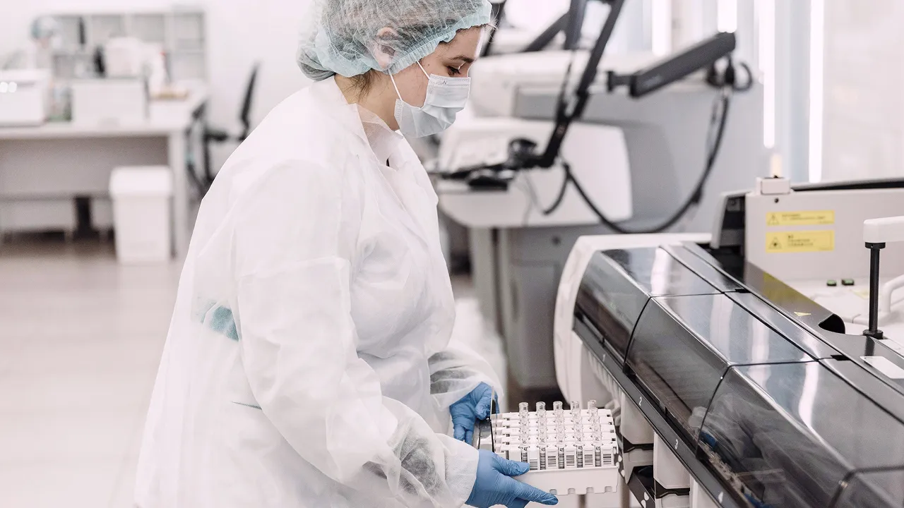 Laboratory technician handling test samples with automated diagnostic equipment.