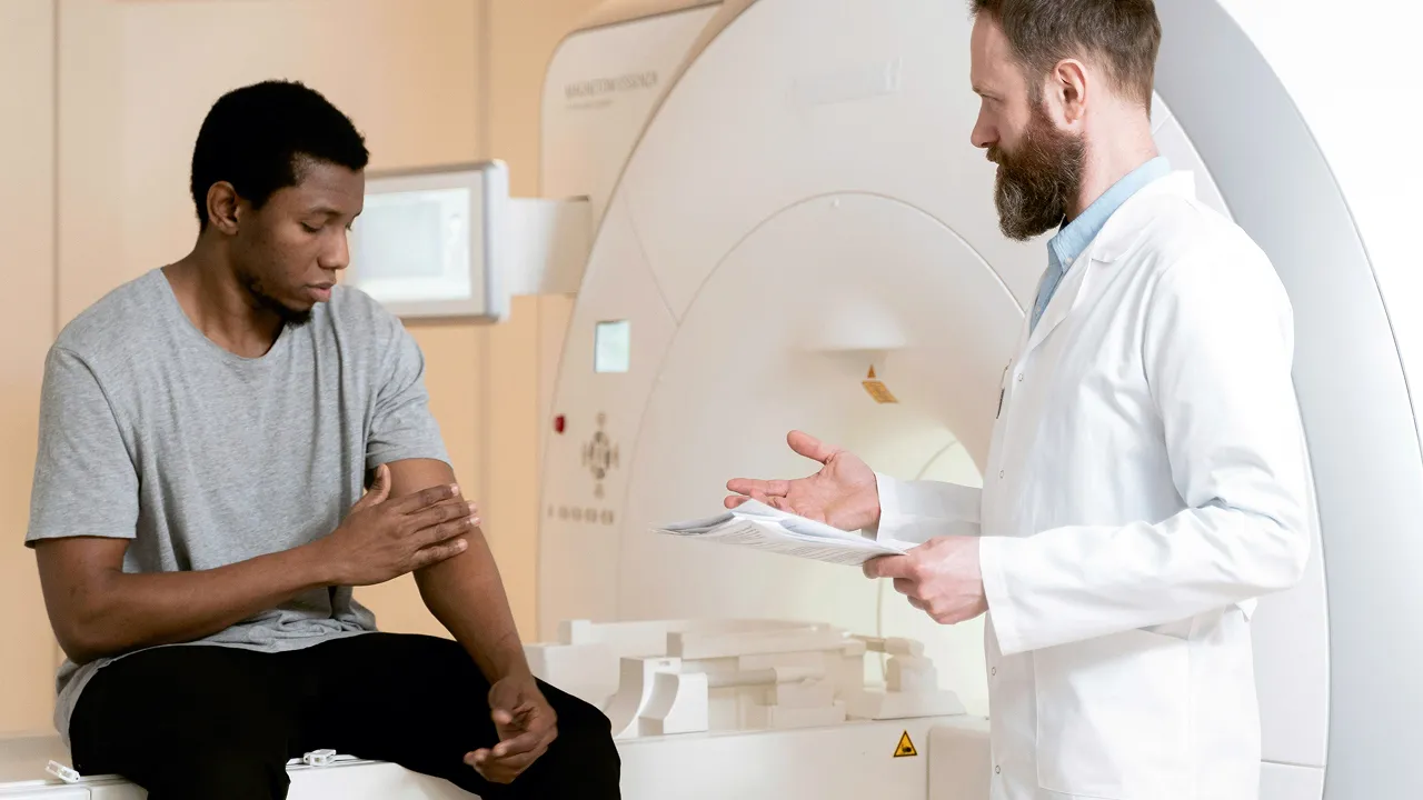 Doctor discussing MRI results with patient beside medical imaging machine.