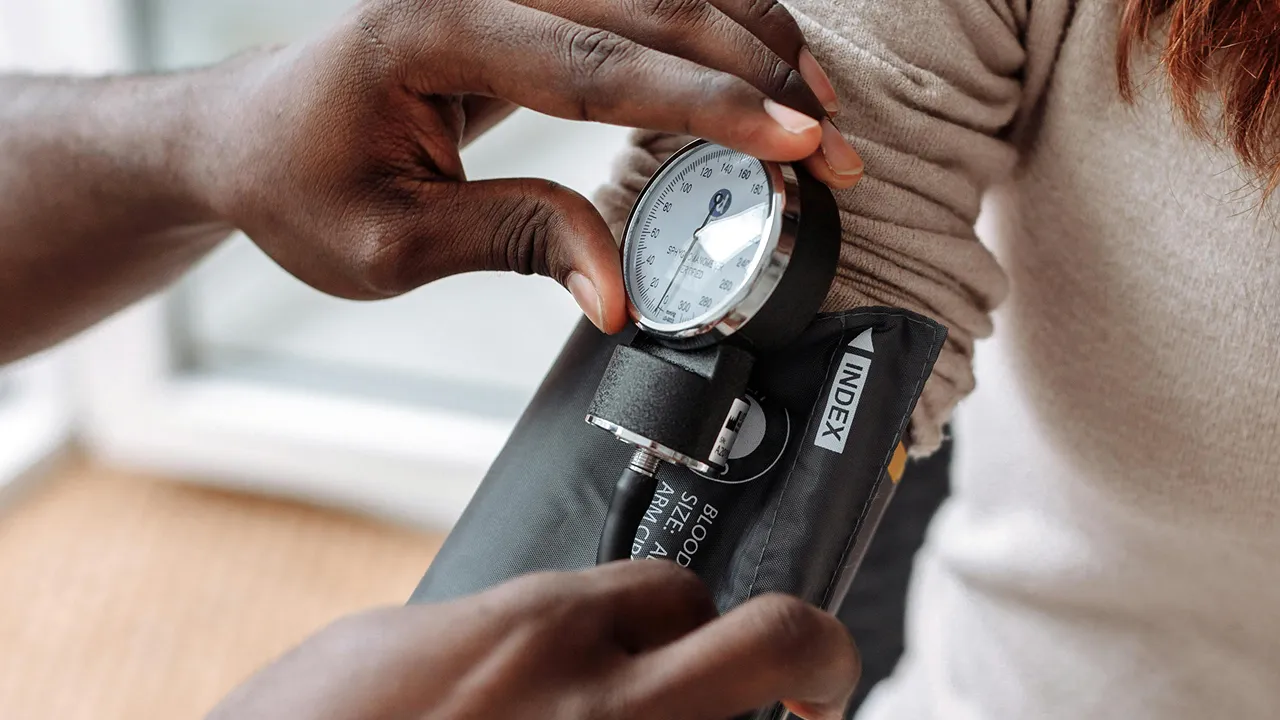 Healthcare professional checking patient’s blood pressure with a manual cuff.