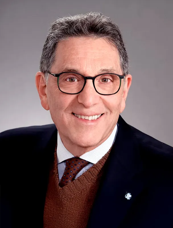 Professional headshot of smiling man wearing glasses, suit, and tie.