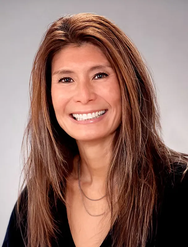 Professional headshot of smiling woman with long hair wearing a black top.