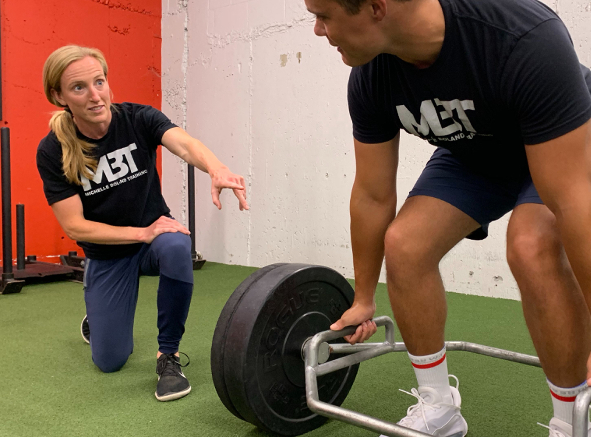 Personal trainer coaching client during strength training session.