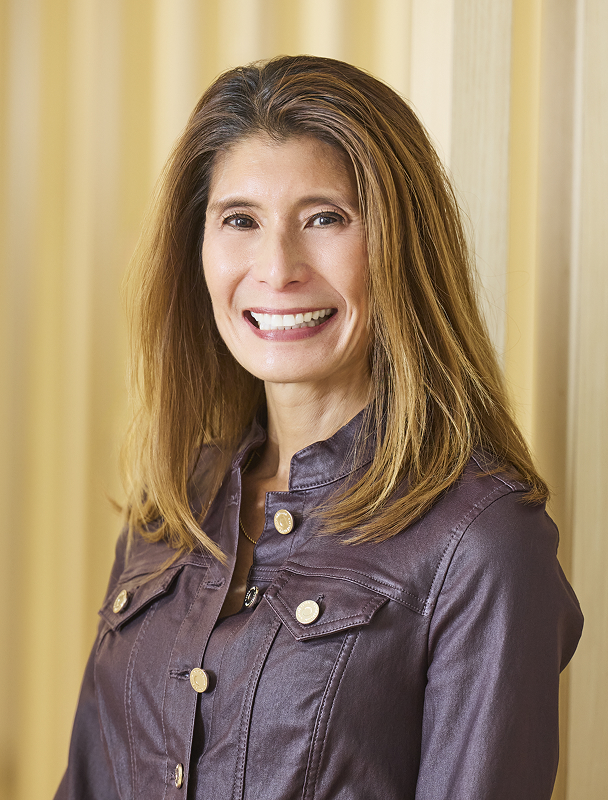 Professional headshot of smiling woman with long hair wearing a black top.