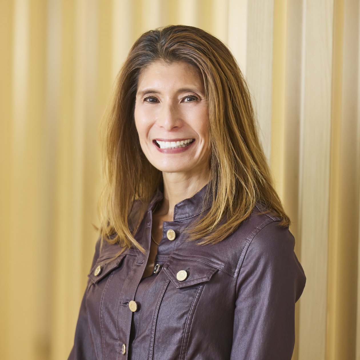 Professional headshot of smiling woman with long hair wearing a black top.