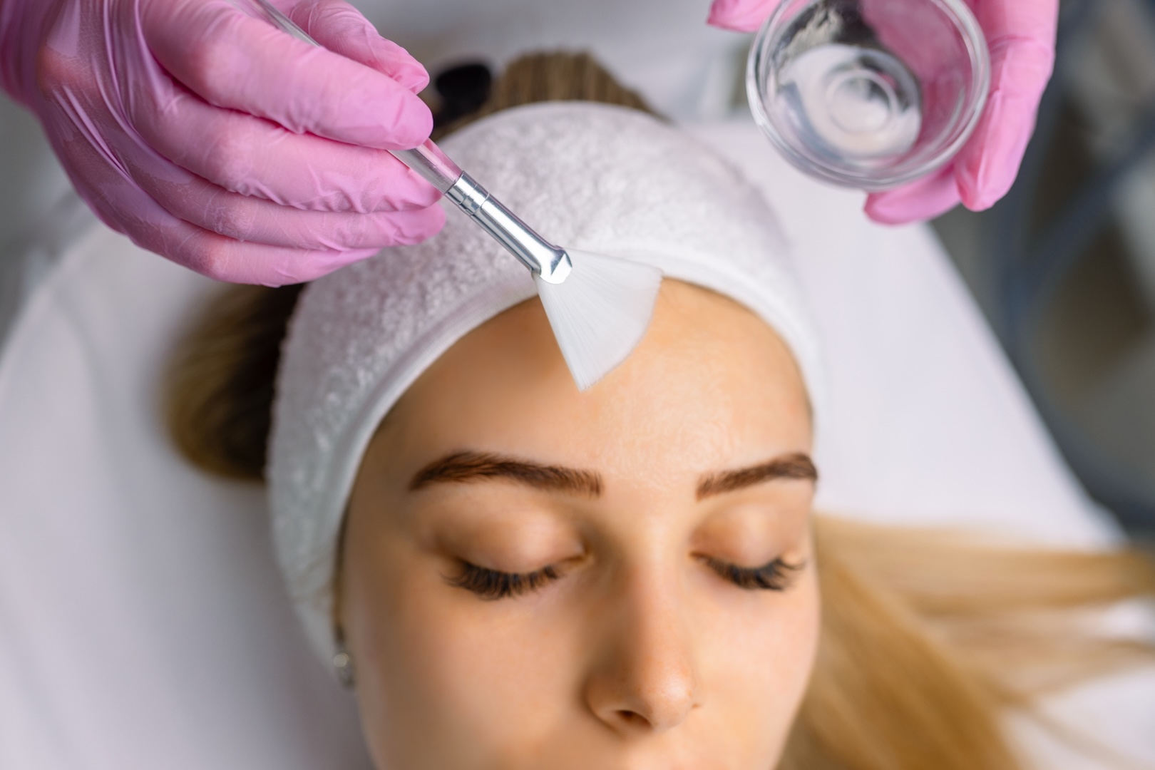 woman having face brushed with liquid