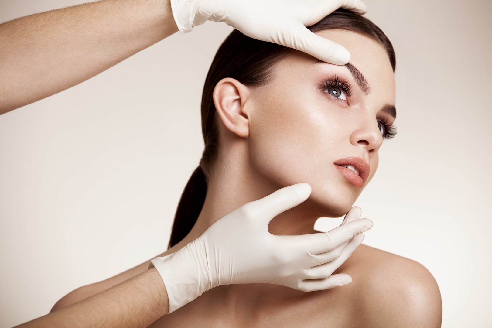 medical gloved hands inspecting woman's face