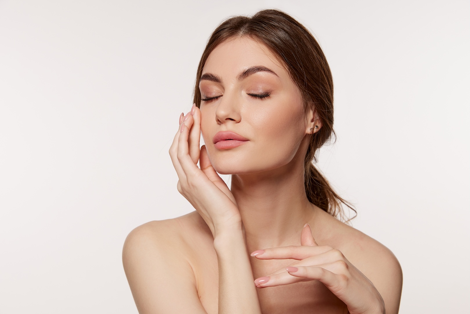 woman with eyes closed touching her face