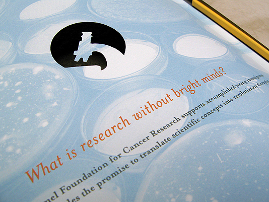 A view of the microscope die cut design with the text "What is research without bright minds?" below it