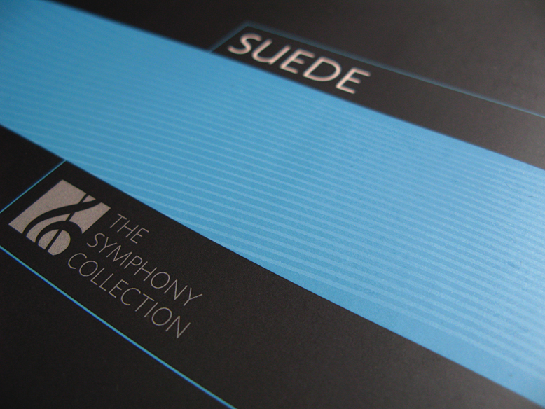 Close up of a swatch folder for the Suede fabrics The Symphony Collection, with a teal colored horizontal bar and wavy lines superimposed on a black background