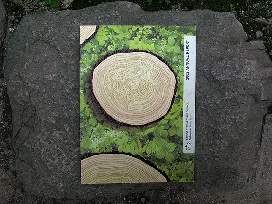 Front cover of an annual report with an illustration of a tree stump cross-section. The rings of the tree form an interlocking image of lumber trucks, trees and people