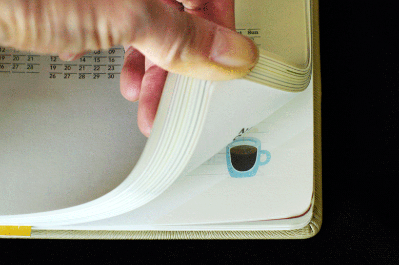 An animated GIF showing a flipbook design on the corner of a Starbucks planner. The flipbook animation shows a glass coffee mug being filled