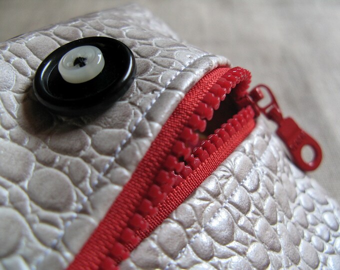 Pouch in the shape of a monster with large button eyes and a red zipper.