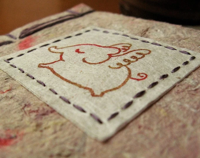 Riso print of a flying elephant, stitched onto the front cover of a hand bound journal