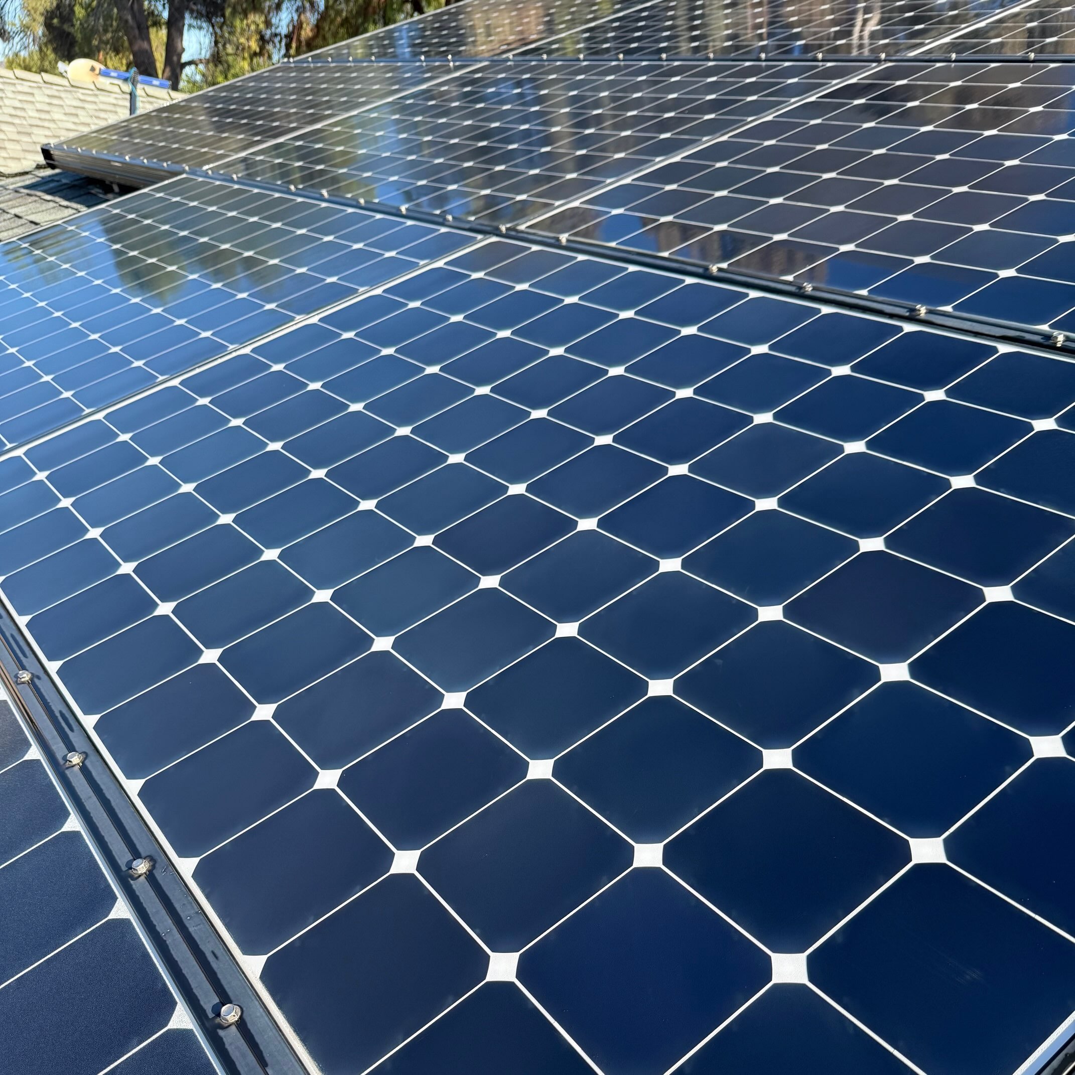 Close-up of multiple dark blue solar panels cleaned on a residential rooftop under sunny sky.