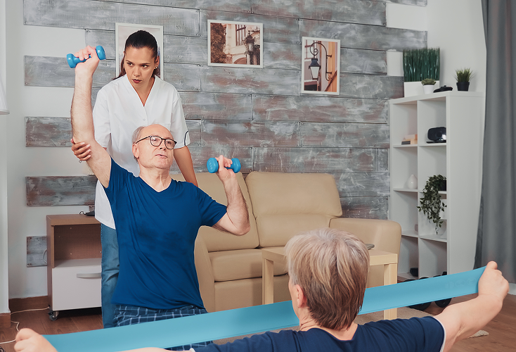A home health care worker the elderly in their exercises.