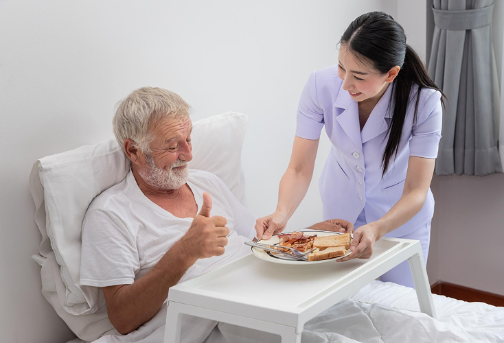 A home health care specialist feeding an elderly man.