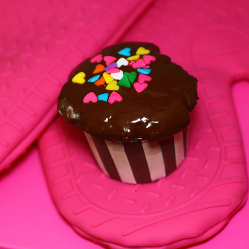 a chocolate cupcake on pink heat resistant gloves