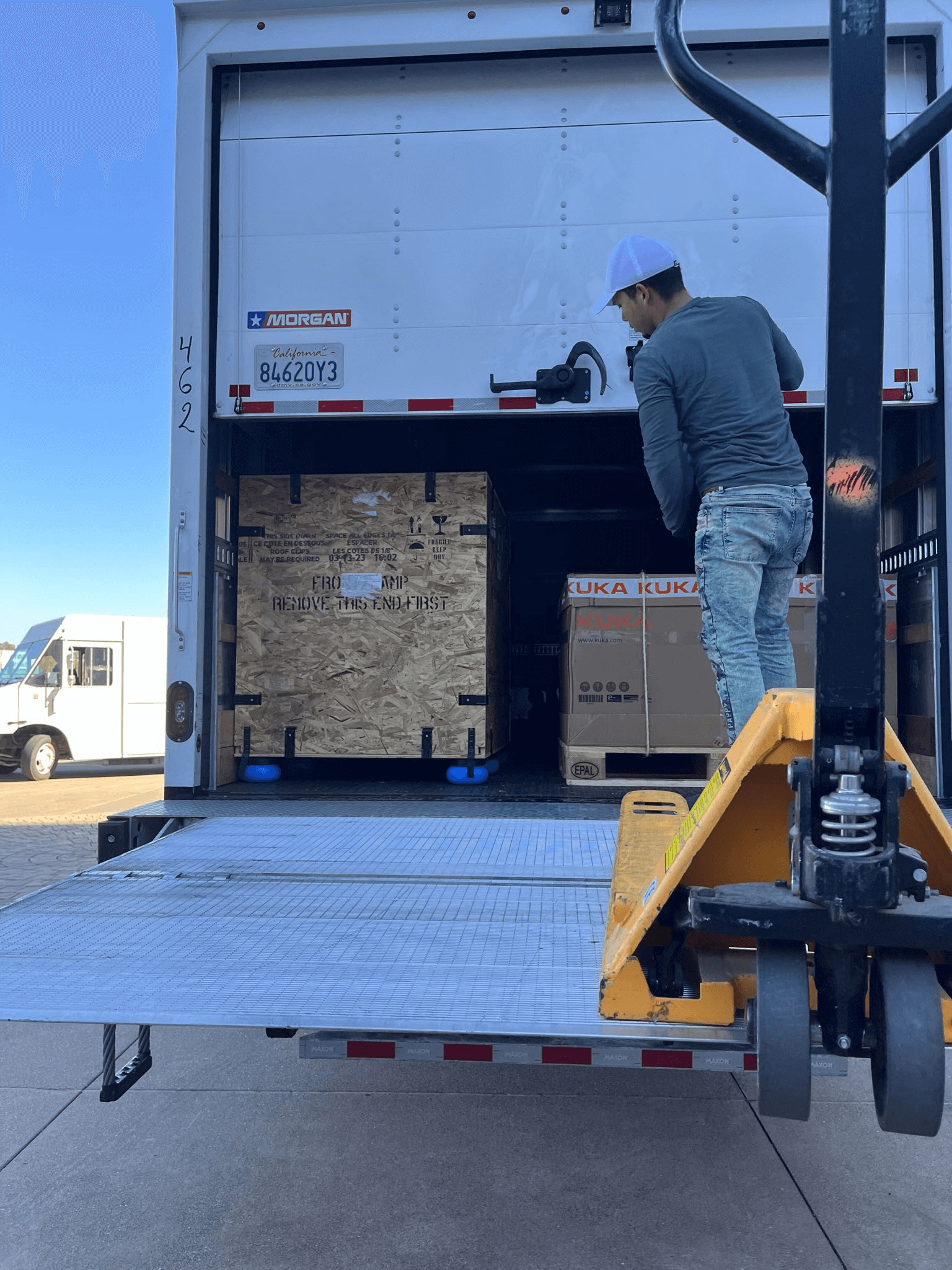 Worker loading Andromeda Surgical robotic system components onto a truck during shipment preparation.