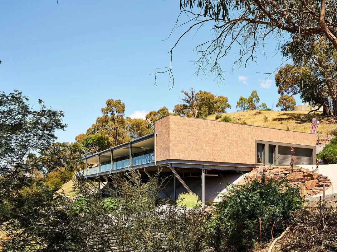 Modern hillside house with stilts and glass railing