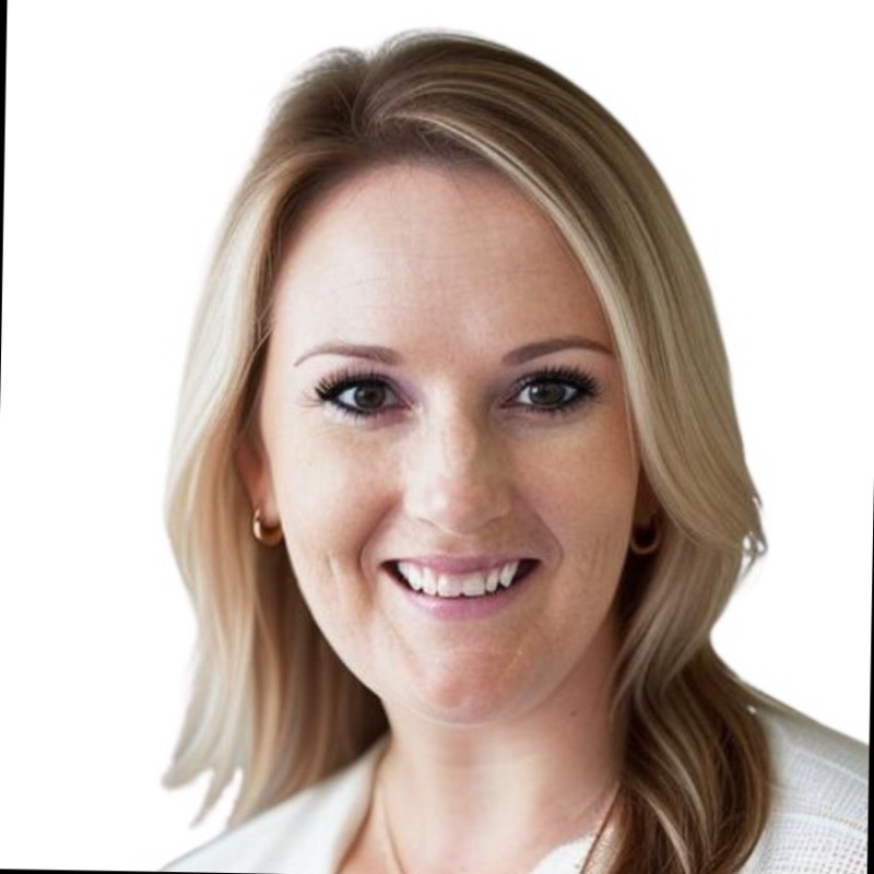 Smiling woman with long blonde hair, wearing small hoop earrings and a white top against a white background.