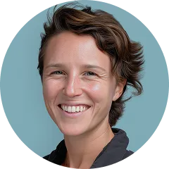 Smiling woman with short wavy brown hair against a blue background.