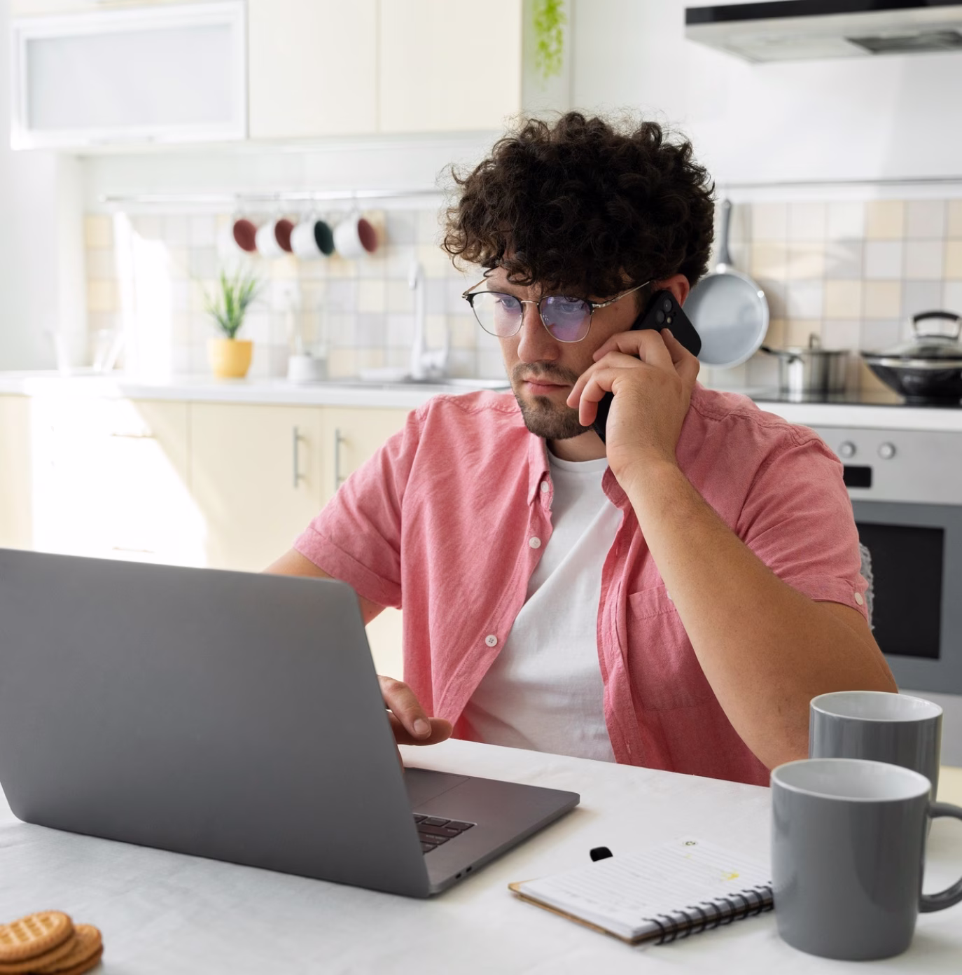 Persoon die op afstand werkt op een laptop terwijl hij een telefoongesprek voert.