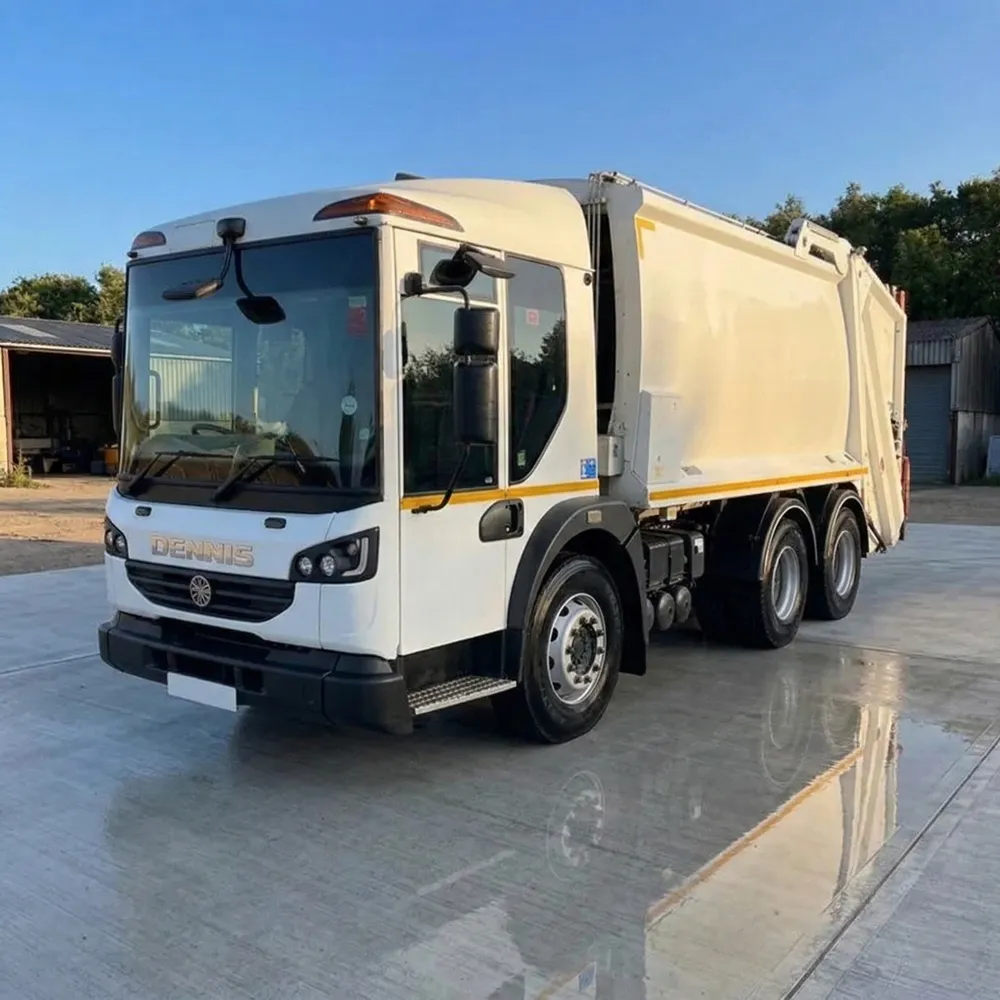 White DAF refuse truck parked on wet concrete in front of a blue industrial building.