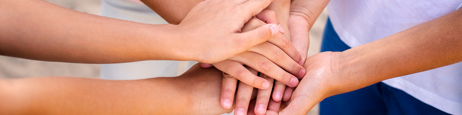 Bild von aufeinander liegenden Händen das Zusammenhalt symbolisiert