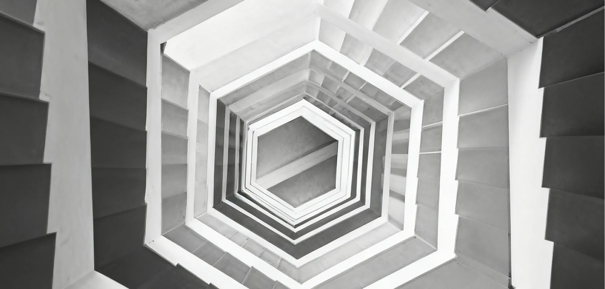 Black and white photo of a hexagonal spiral staircase viewed from below.