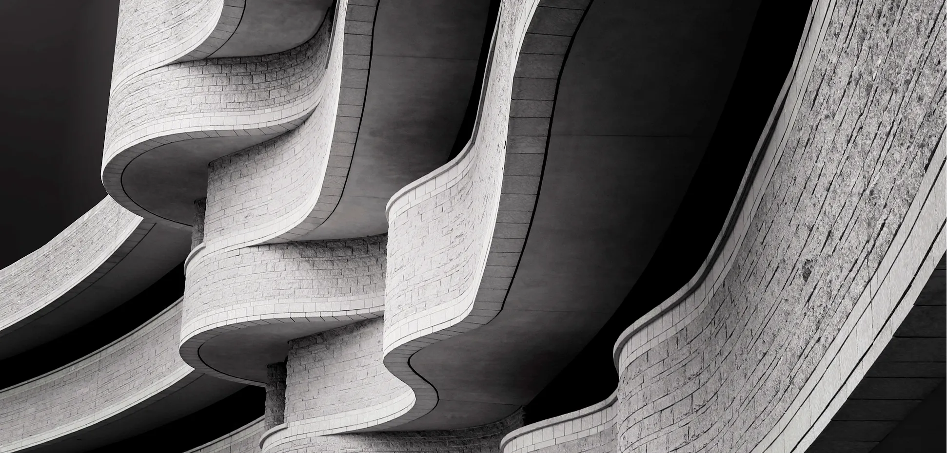 Close-up of modern architectural structure featuring curved concrete balconies with stone cladding in black and white.