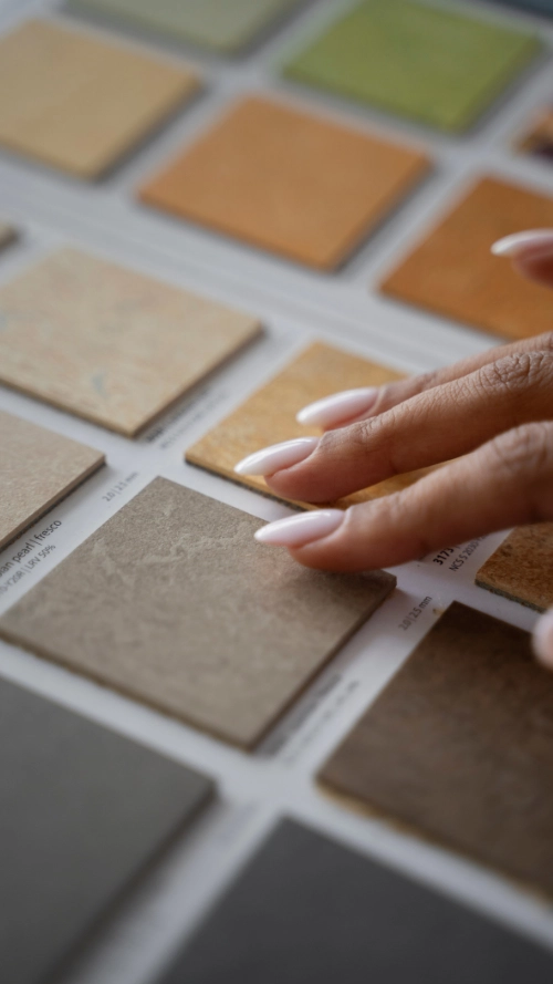 Architectural workspace with color swatches, blueprint on a tablet, drafting tools, pencils, and a keyboard arranged on a blue surface.