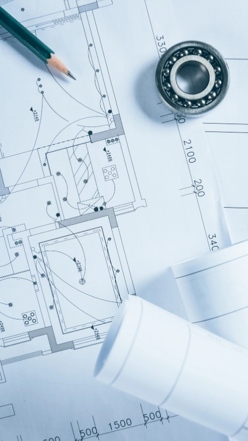 Architectural blueprints with rolled-up plans and two wooden pencils on a white surface.