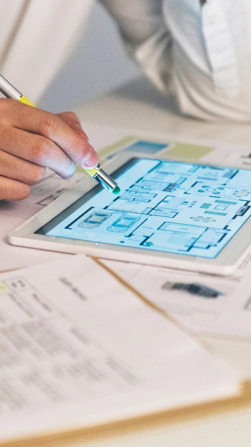 Person working on a computer showing 3D modeling of robotic arms in an industrial design software.