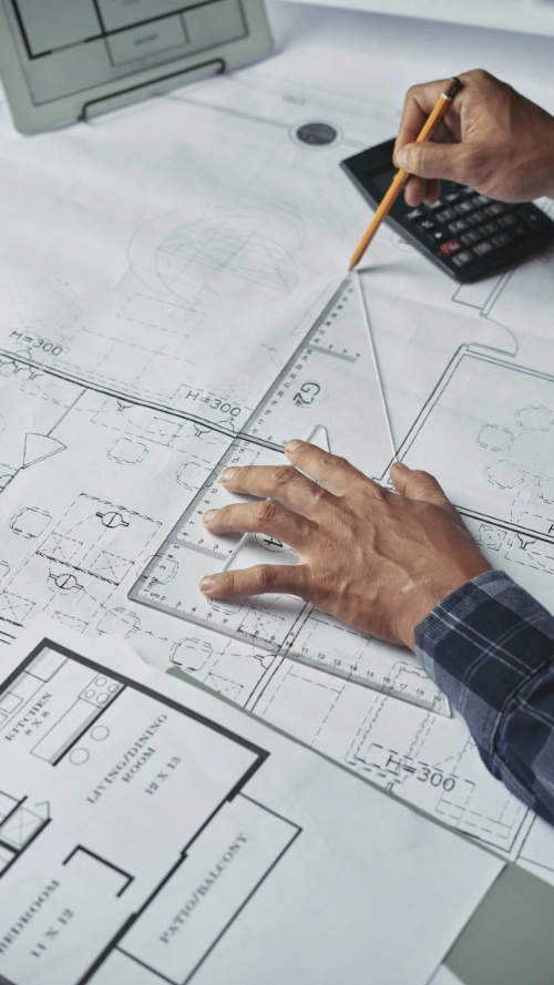 Modern glass house with flat roof surrounded by blue-toned trees reflected in calm water.
