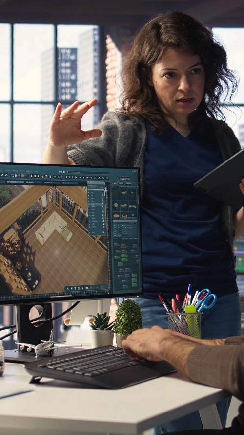 Person writing on a clipboard over architectural blueprints while another points at the plans with a finger.