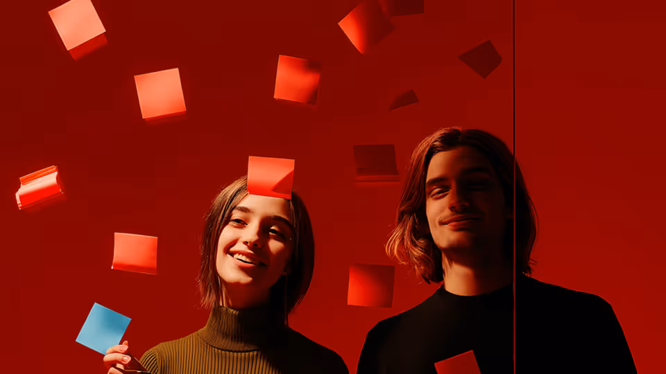 Two young people smiling with red sticky notes falling around them against a red background.