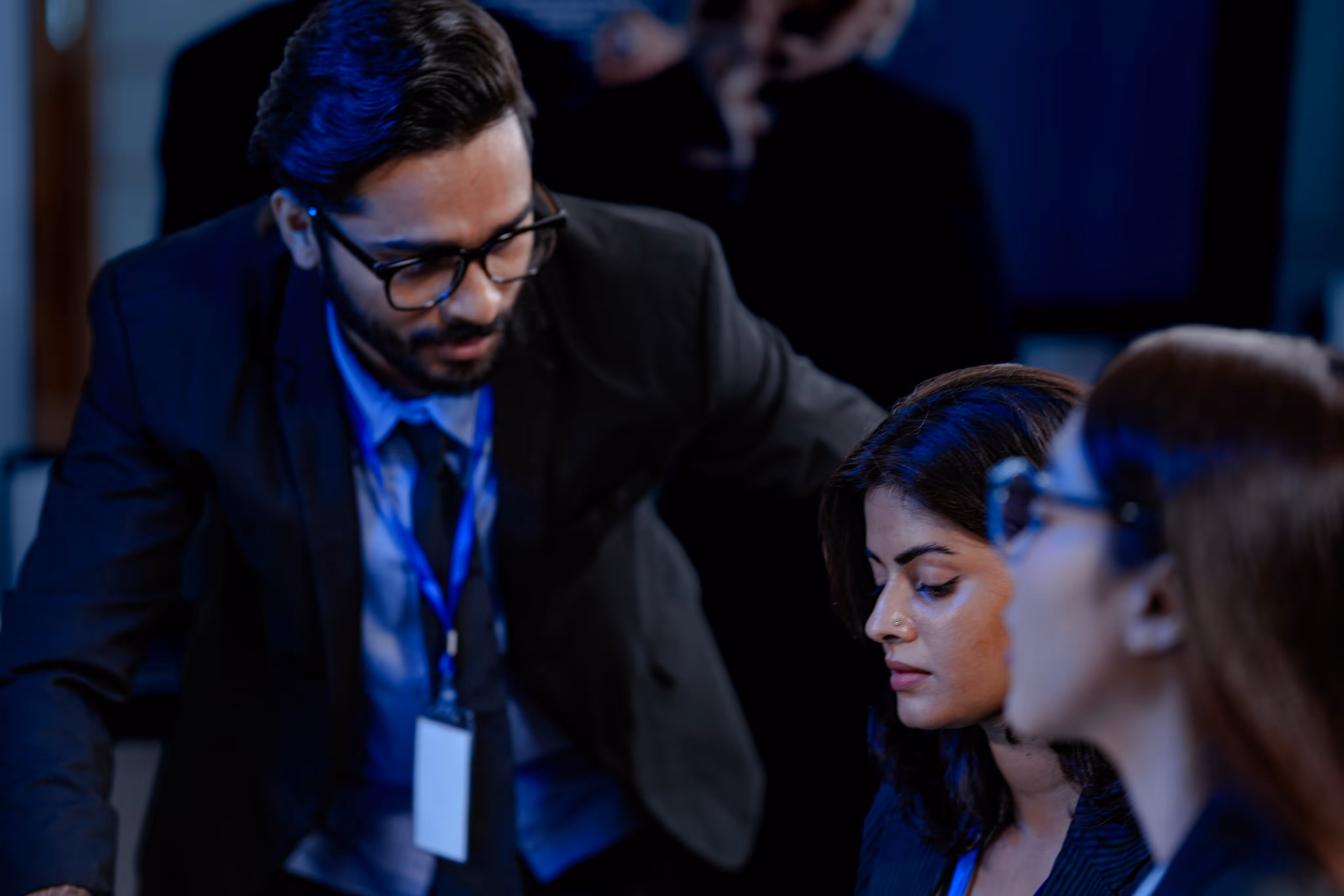Three business professionals in formal attire engaged in a discussion in an office setting.