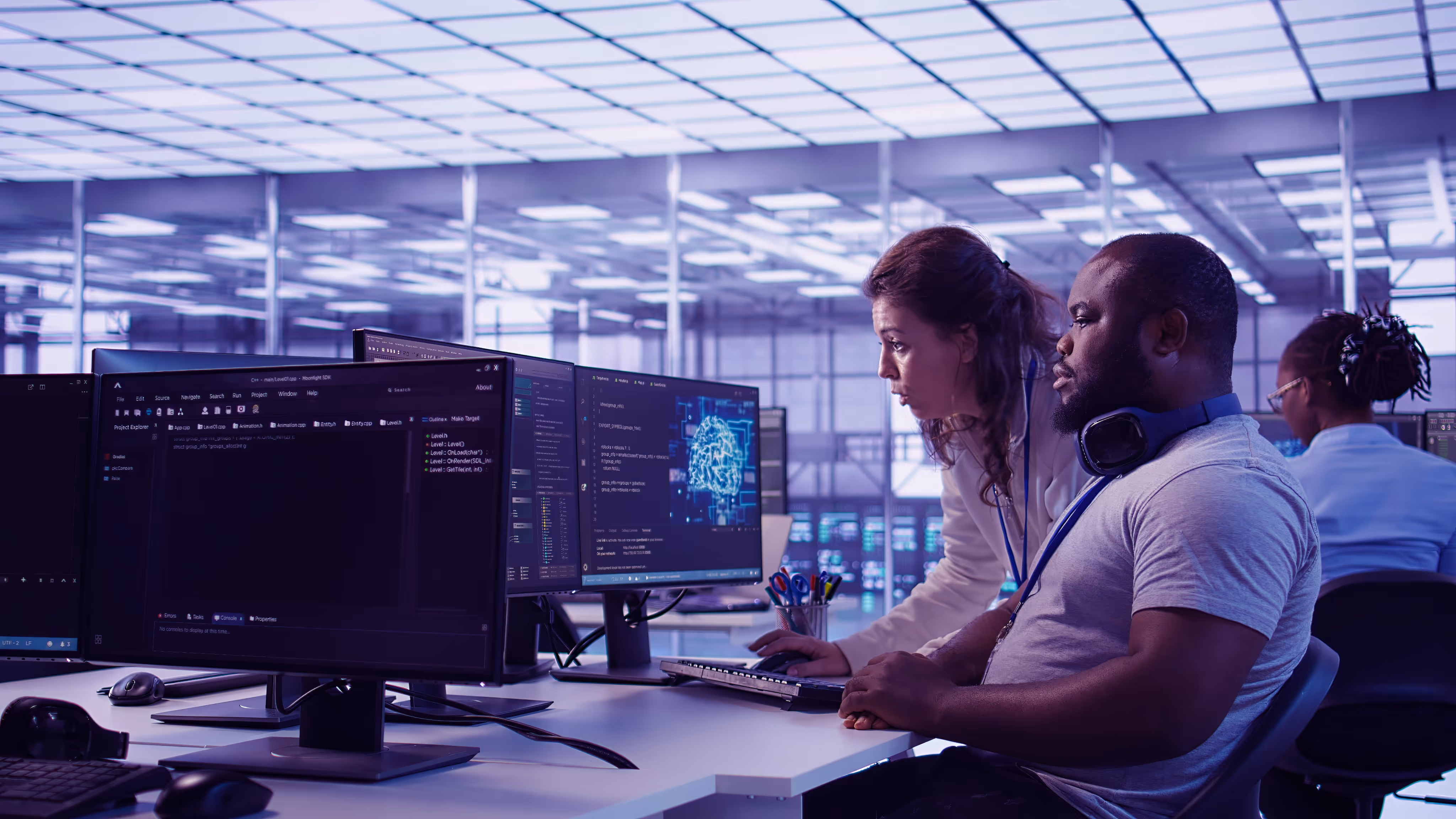 Two coworkers focused on computer screens displaying code and a digital brain in a modern office.