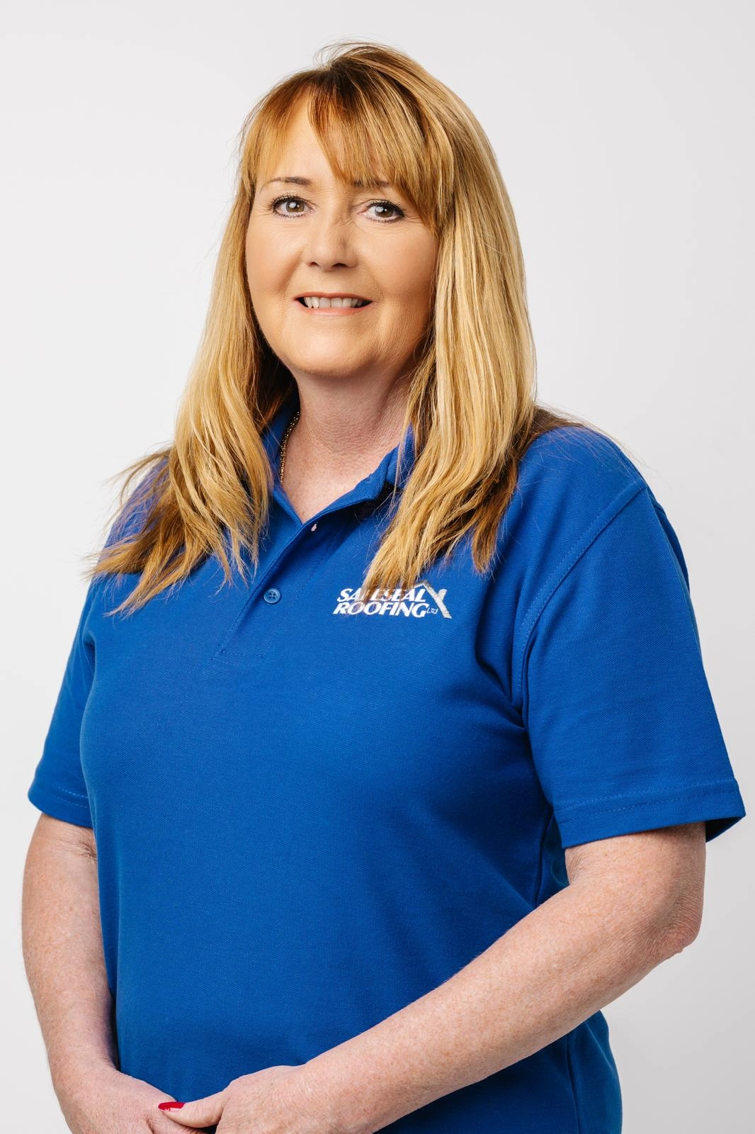 Smiling woman with long blonde hair wearing a blue polo shirt with 'Salt Real Roofing' logo on a white background.