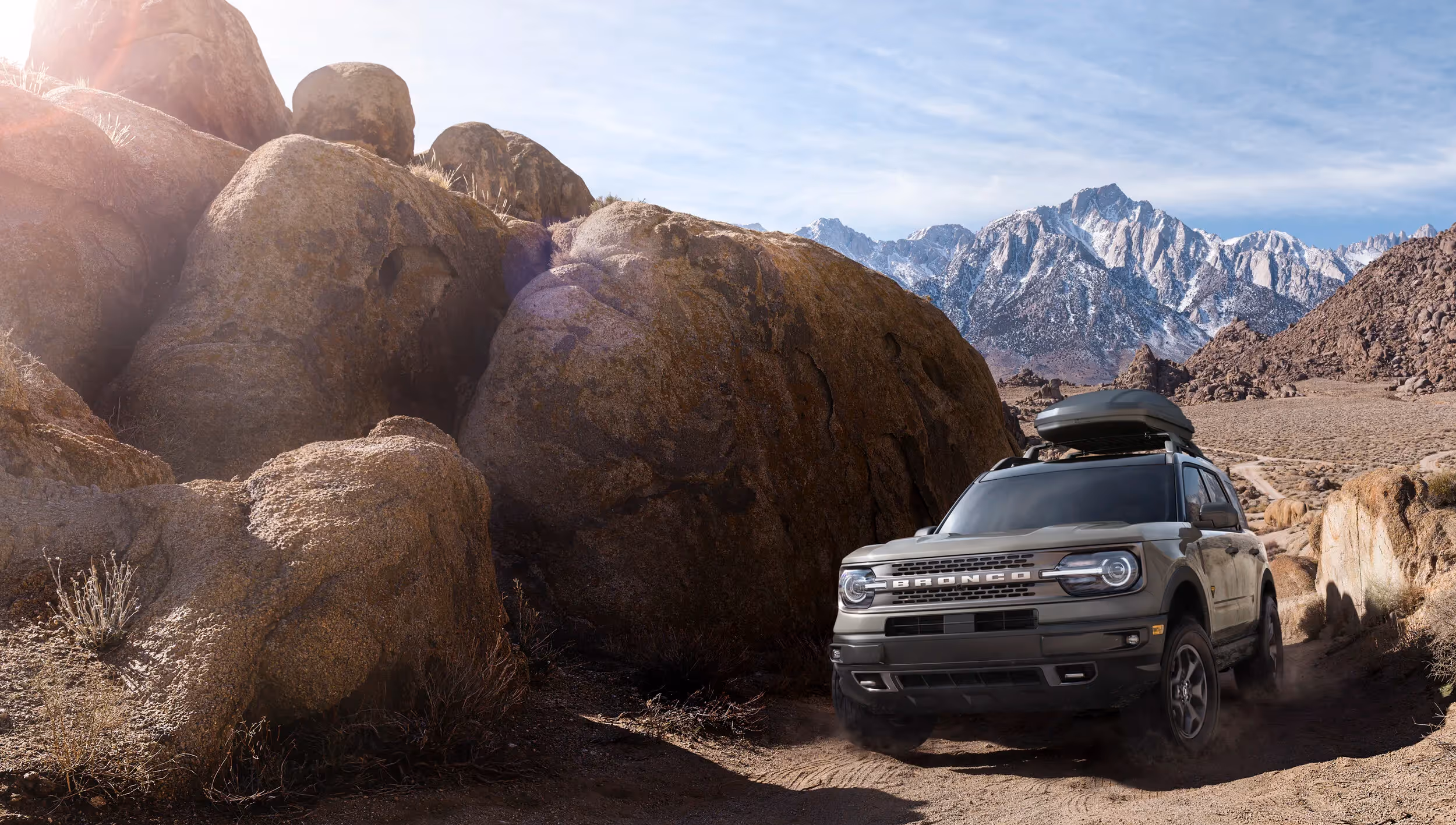 Ford Bronco Sport navigating rocky desert terrain with snowcapped mountains in background, rugged adventure automotive photography by Roe Photo.