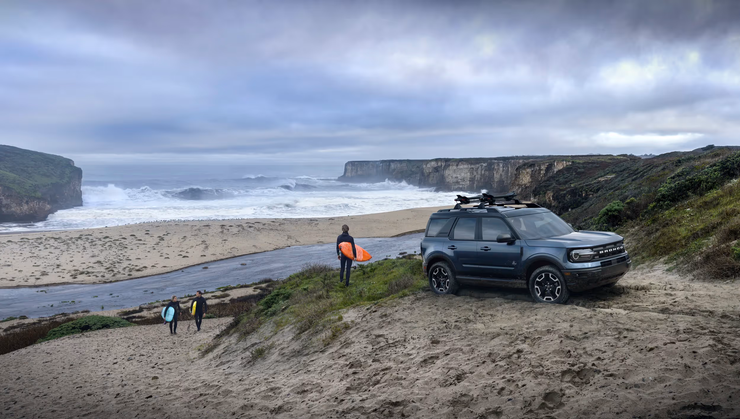 Ford Bronco Sport on coastal bluff as surfers head to the ocean, outdoor lifestyle and surf adventure photography by Roe Photo.
