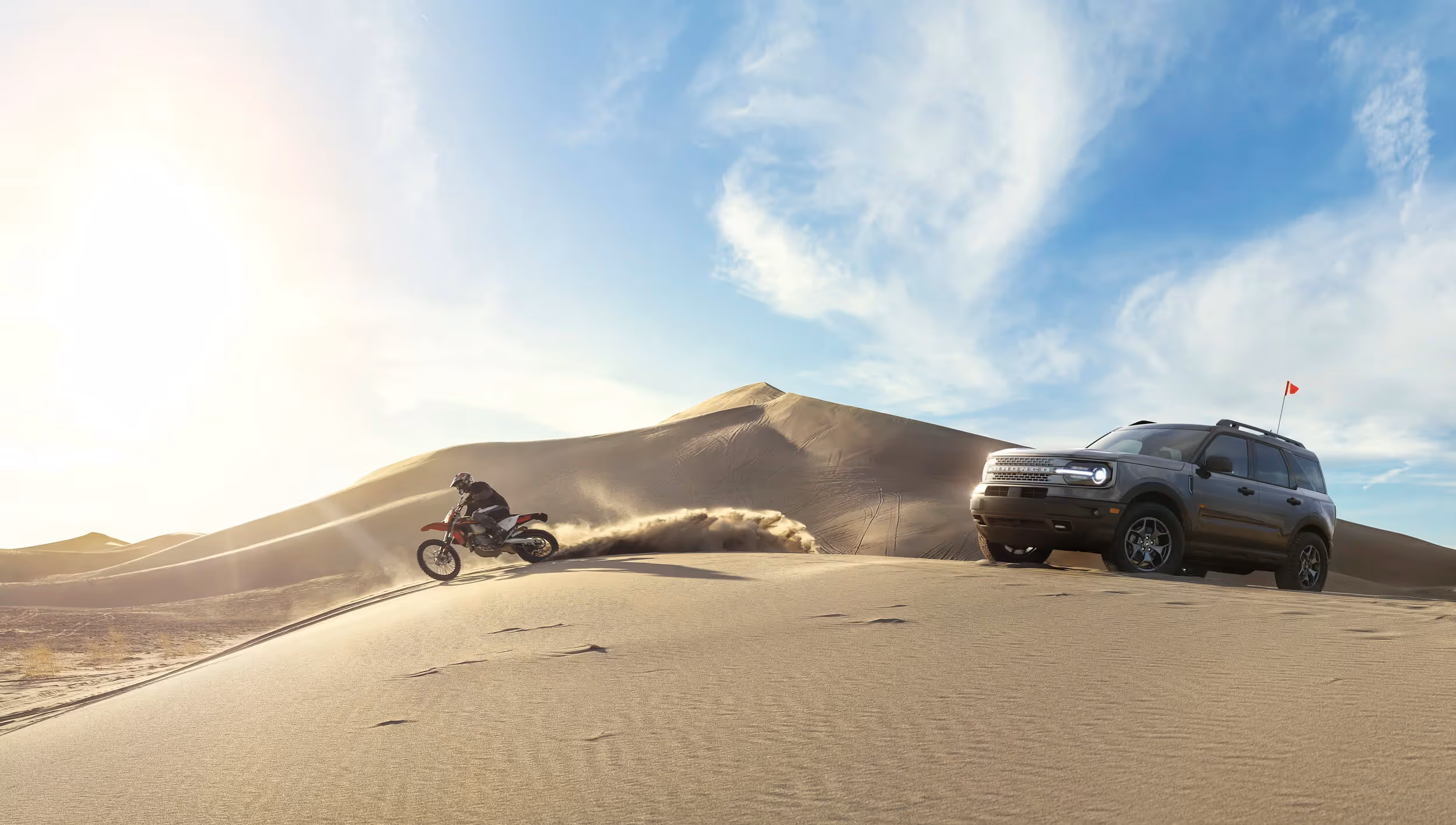 Ford Bronco Sport in sand dunes beside motorcyclist riding through desert, off-road adventure automotive photography by Roe Photo.