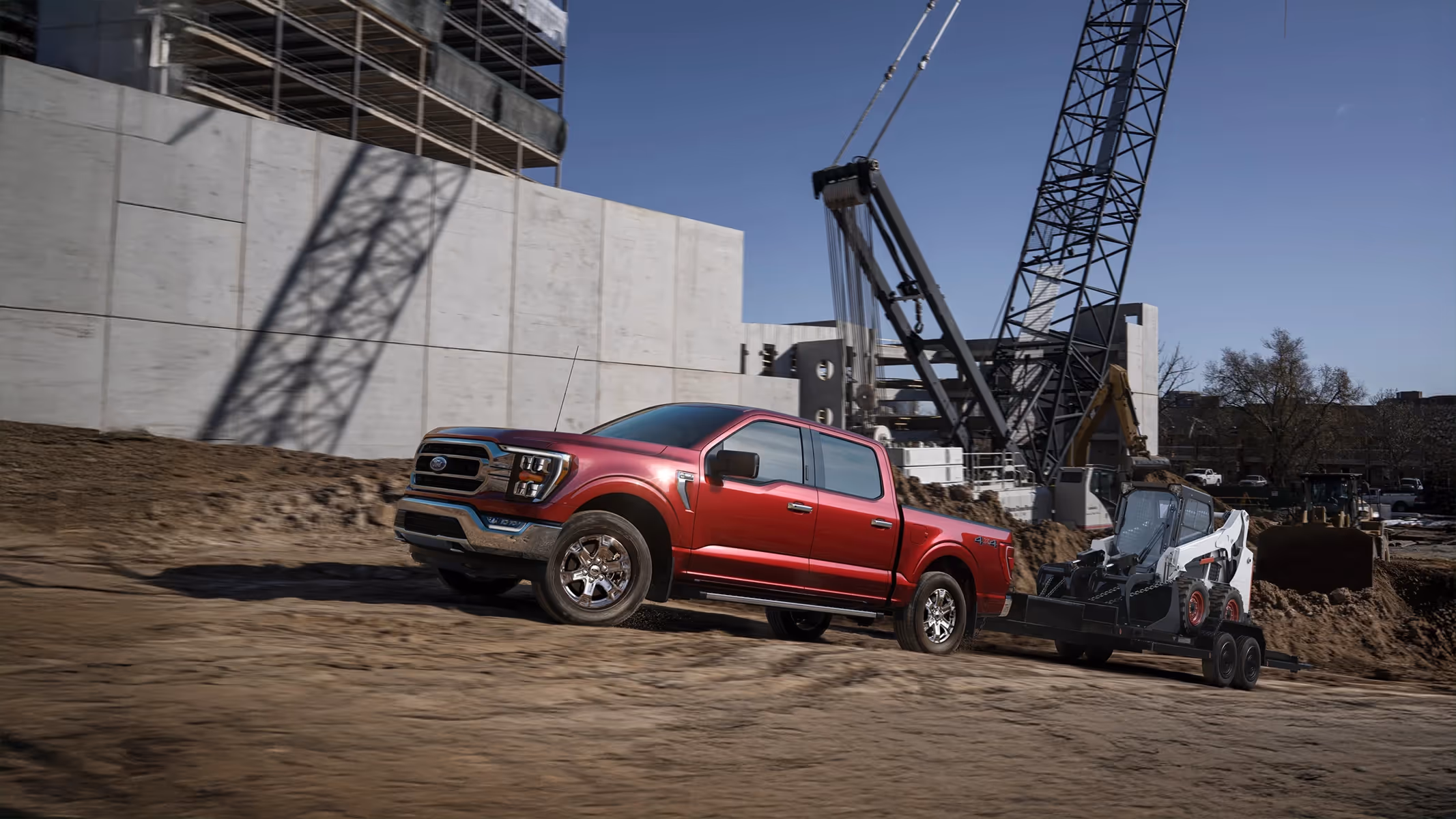 Red Ford F-150 launching a boat at sunrise by the river, bridge structure visible in background.