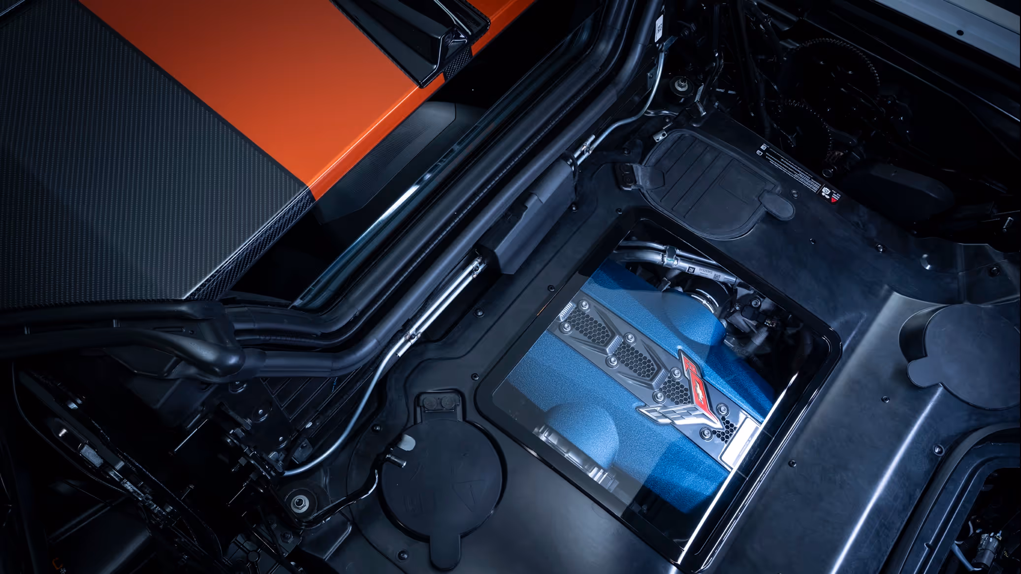 Overhead engine compartment shot revealing the mid-mounted powertrain of the Corvette ZR1 under studio lighting.