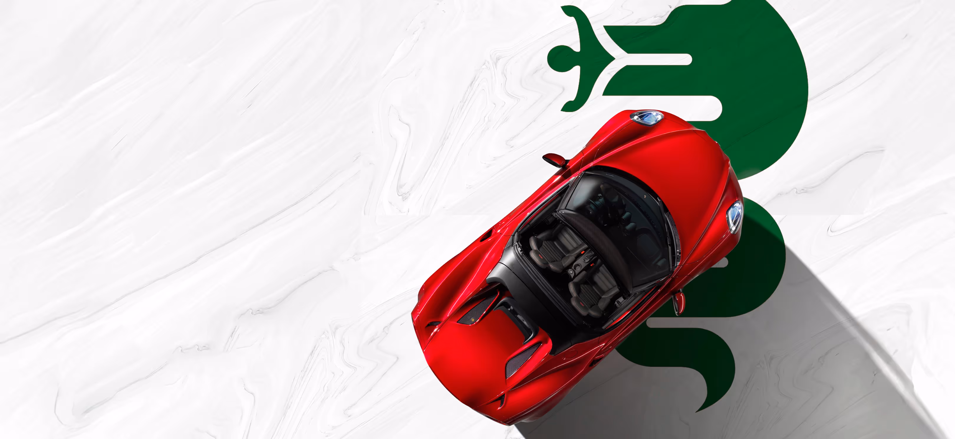 Overhead studio shot of red Alfa Romeo 4C on a white marble floor with a large green cloverleaf symbol.