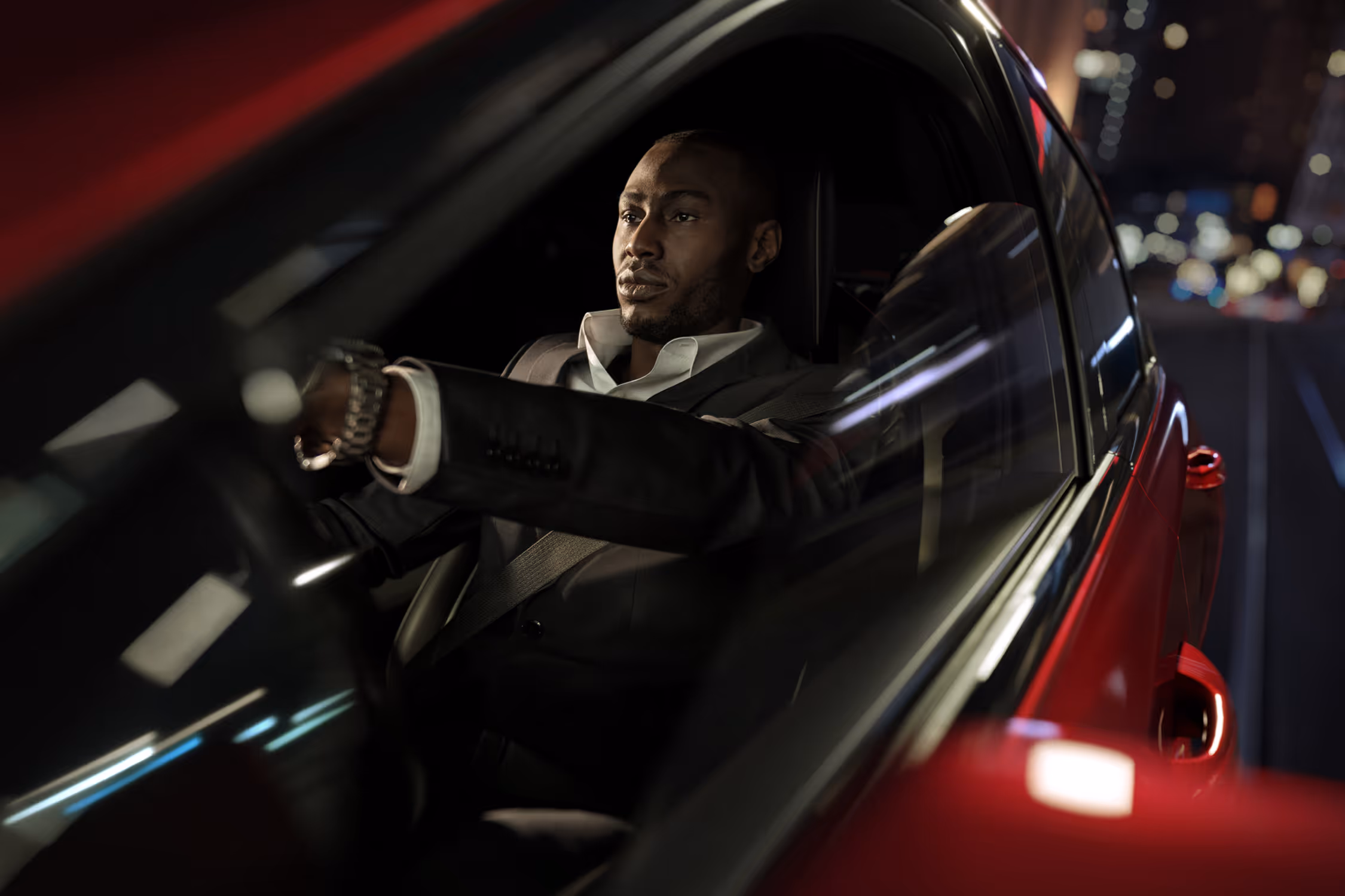 Man driving red Cadillac CT5 through the city at night, captured in cinematic interior lighting.
