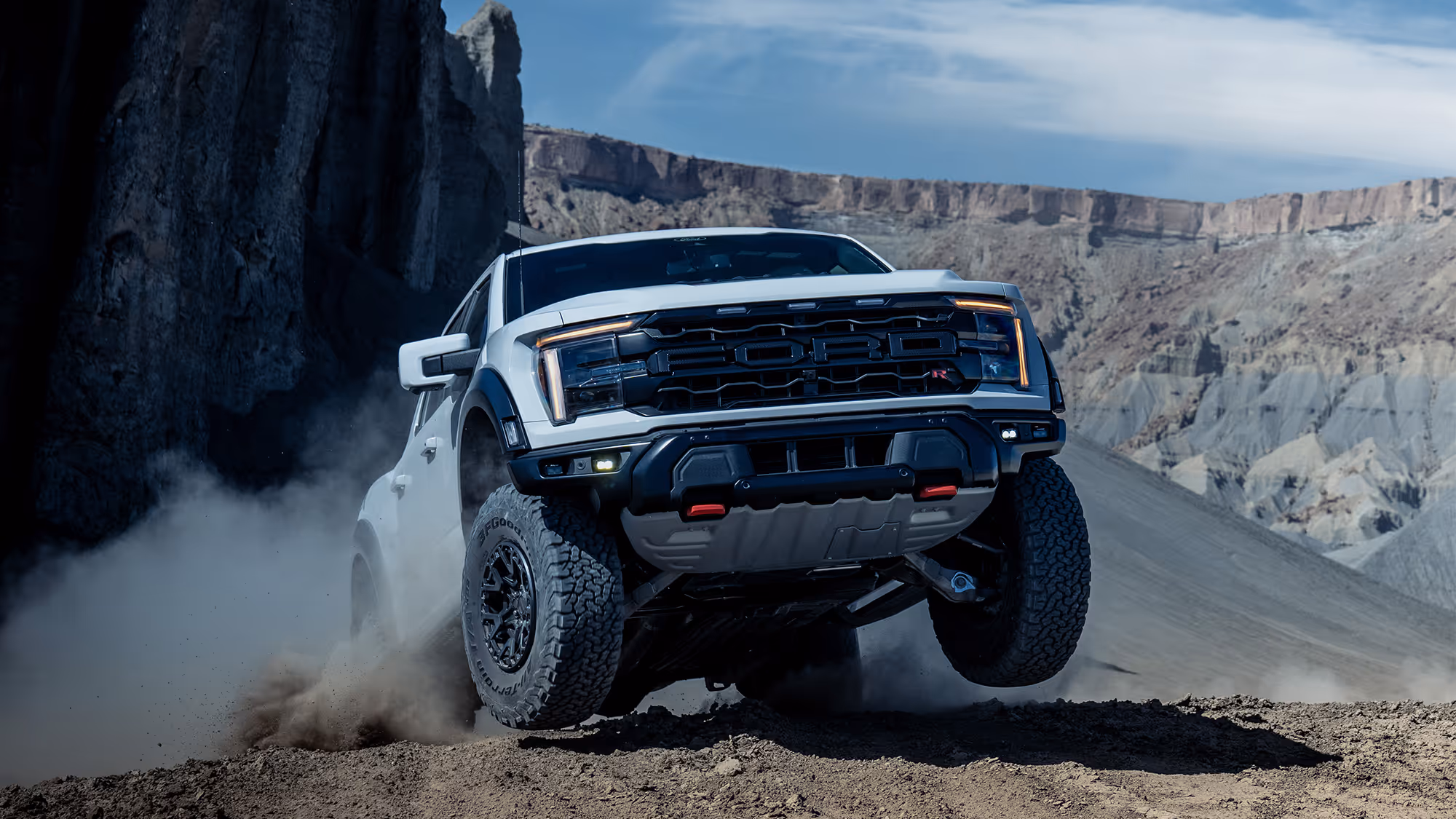 Ford Raptor R climbing steep rocky terrain with dust in desert landscape