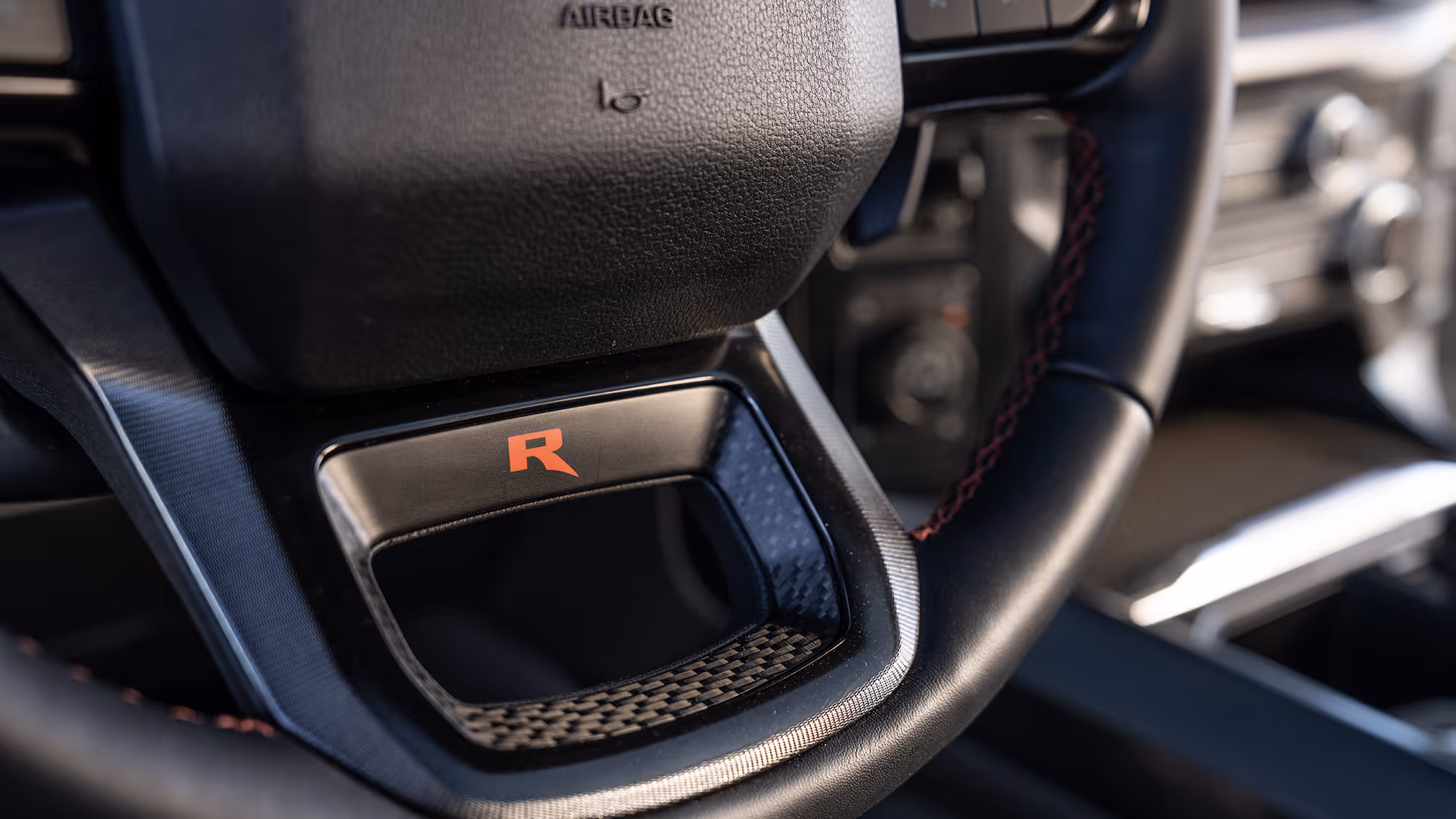 Close-up of Ford Raptor R steering wheel with red accent badge and textured grip