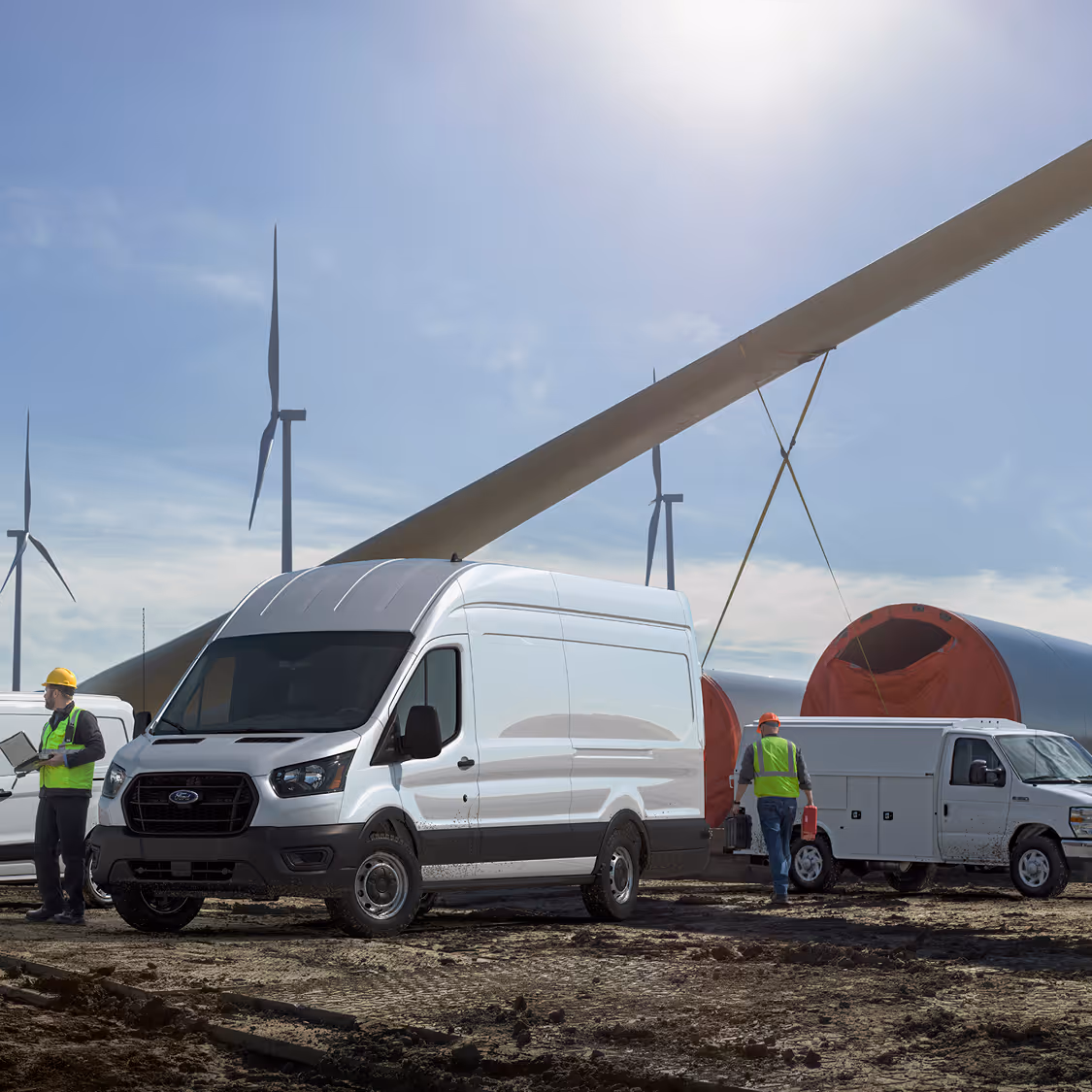 Ford Transit van and work trucks at wind farm site with crew coordinating near turbine blades